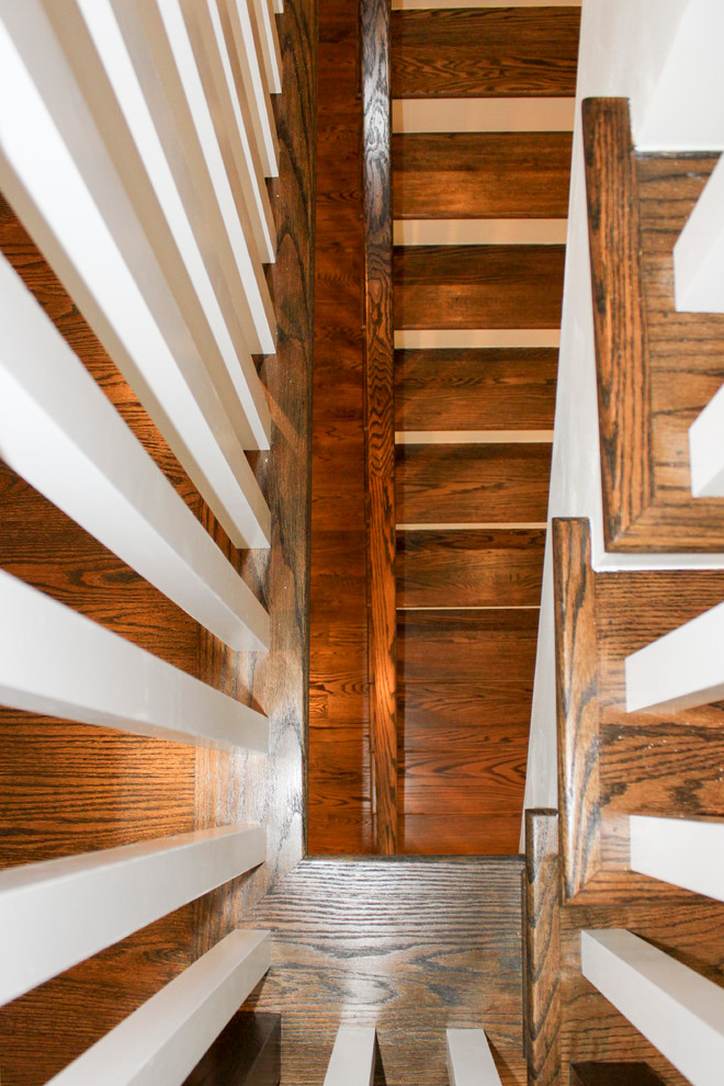 Ejemplo de escalera suspendida ecléctica grande con escalones de madera, contrahuellas de madera y barandilla de madera