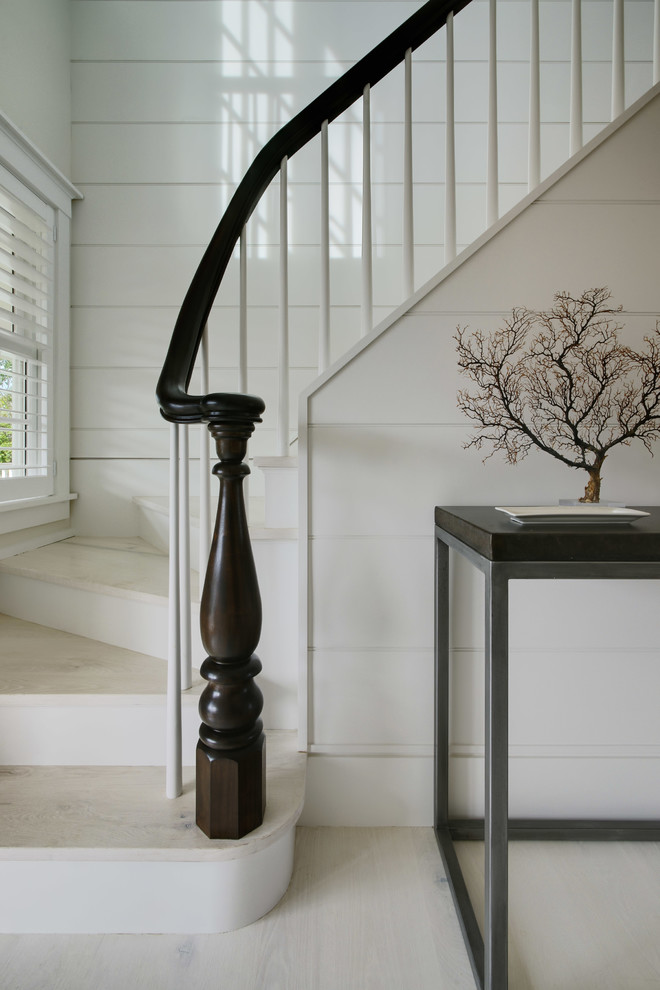 Пример оригинального дизайна: изогнутая лестница среднего размера в стиле неоклассика (современная классика) с деревянными ступенями и крашенными деревянными подступенками