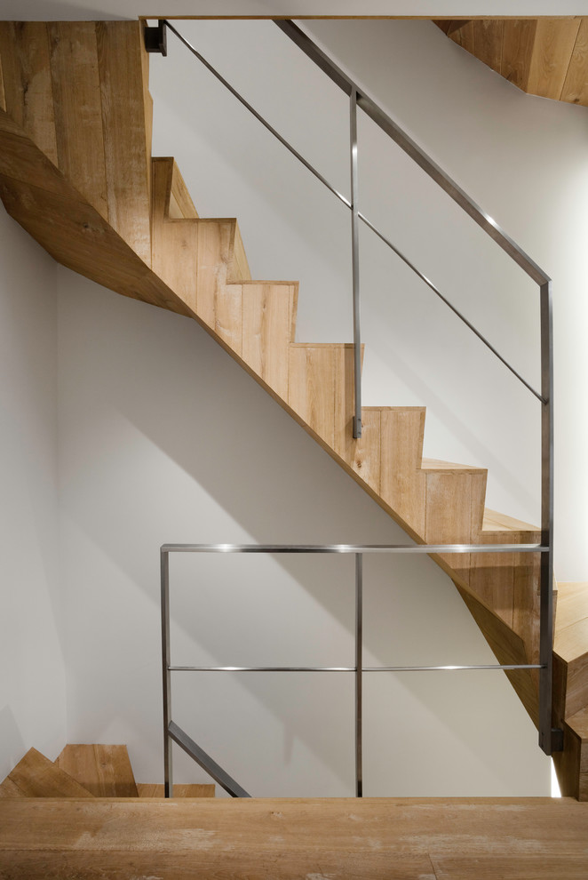 Inspiration pour un escalier courbe minimaliste avec des marches en bois, des contremarches en bois, un garde-corps en métal et palier.