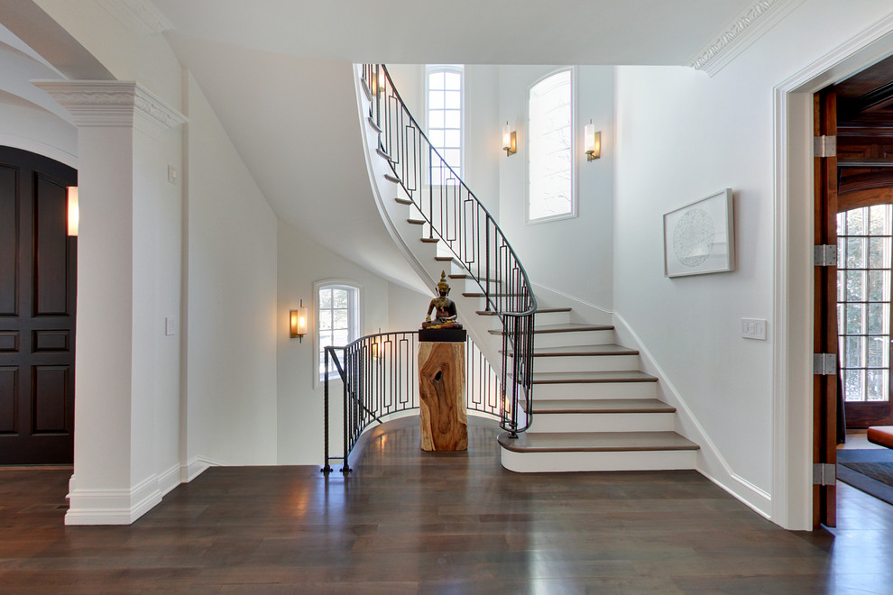 На фото: изогнутая лестница среднего размера в современном стиле с деревянными ступенями, крашенными деревянными подступенками и металлическими перилами с