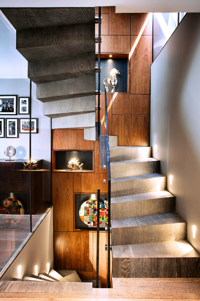 Imagen de escalera curva actual con escalones de madera, contrahuellas de madera y barandilla de vidrio