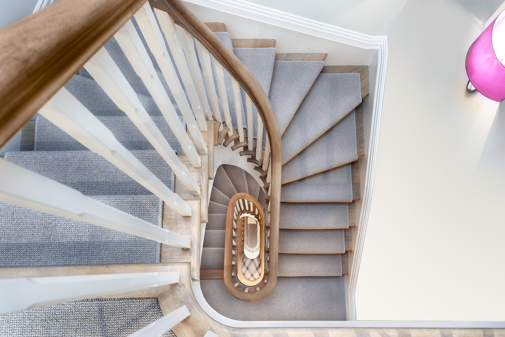 Imagen de escalera en U contemporánea grande con escalones enmoquetados, contrahuellas de madera y barandilla de madera