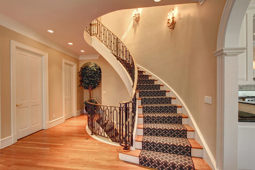 Пример оригинального дизайна: огромная винтовая деревянная лестница в классическом стиле с ступенями с ковровым покрытием