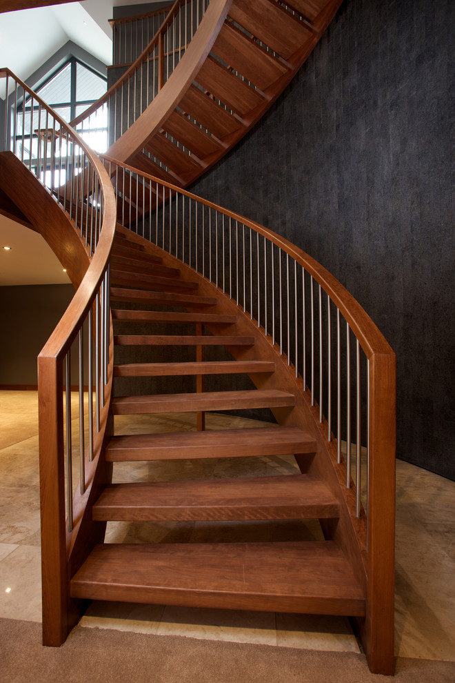 Ejemplo de escalera curva de estilo americano sin contrahuella con escalones de madera y barandilla de madera