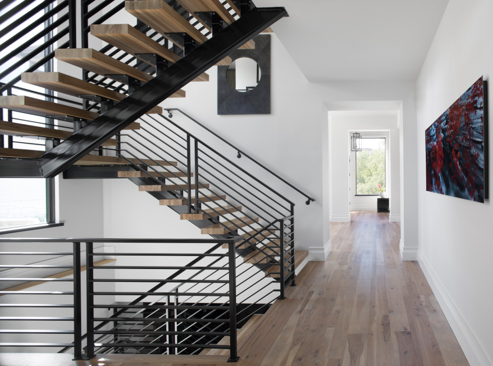 Стильный дизайн: большая лестница на больцах в современном стиле с деревянными ступенями и металлическими перилами - последний тренд