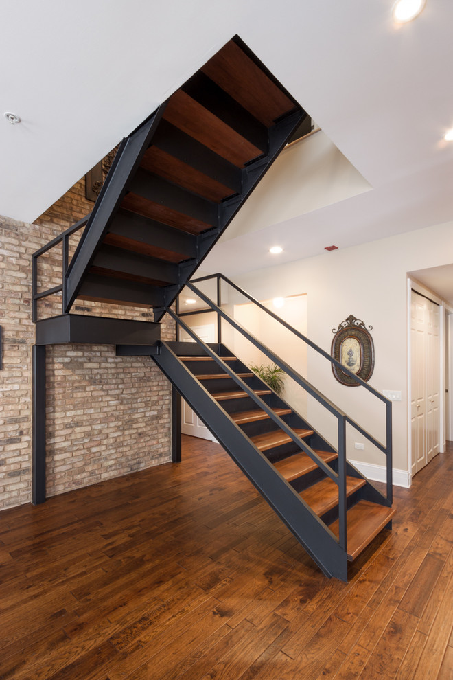 Cette image montre un grand escalier design en U avec des marches en bois et des contremarches en métal.