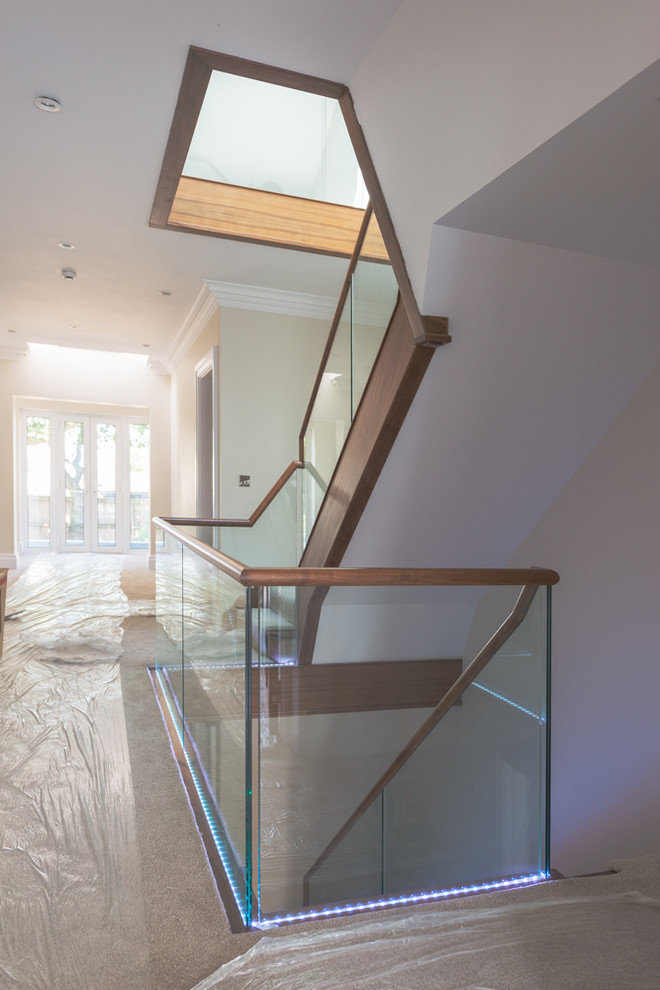 Design ideas for a large modern wood l-shaped staircase in London with wood risers.