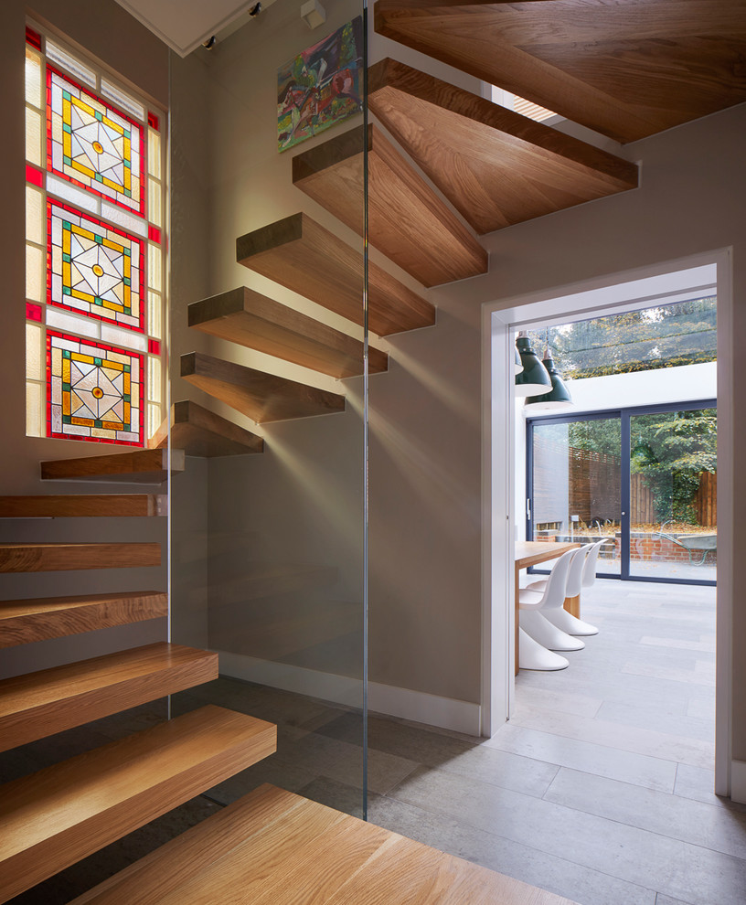 Diseño de escalera suspendida actual sin contrahuella con escalones de madera y barandilla de vidrio
