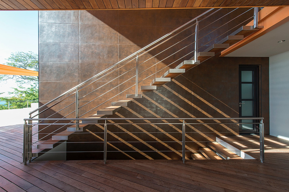 Cette photo montre un escalier flottant tendance avec des marches en bois et un garde-corps en métal.