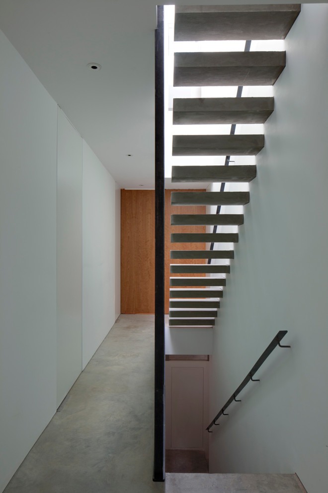 Photo of a contemporary straight staircase in London with concrete risers.