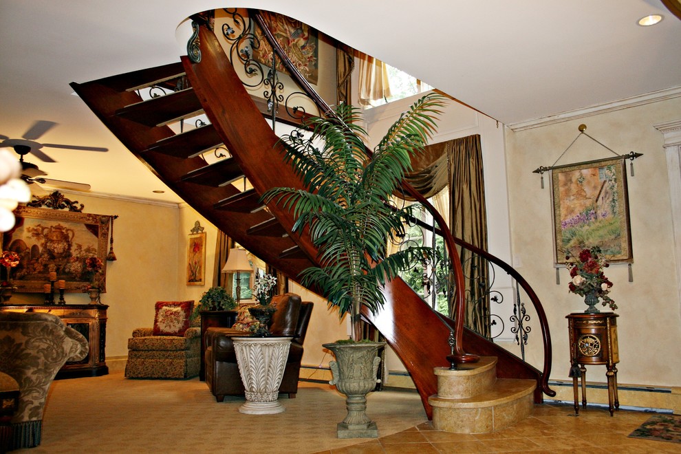 Exempel på en stor klassisk svängd trappa i travertin, med sättsteg i travertin och räcke i metall