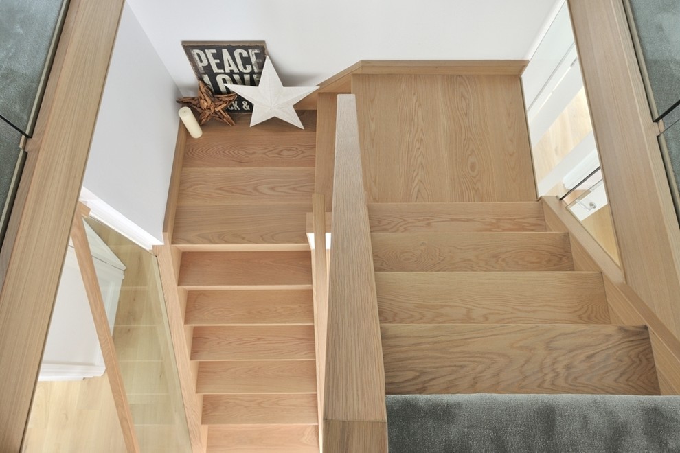 На фото: изогнутая лестница среднего размера в классическом стиле с деревянными ступенями, стеклянными подступенками и деревянными перилами с