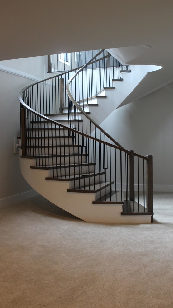 Imagen de escalera curva clásica renovada grande con escalones de madera, contrahuellas de madera y barandilla de varios materiales