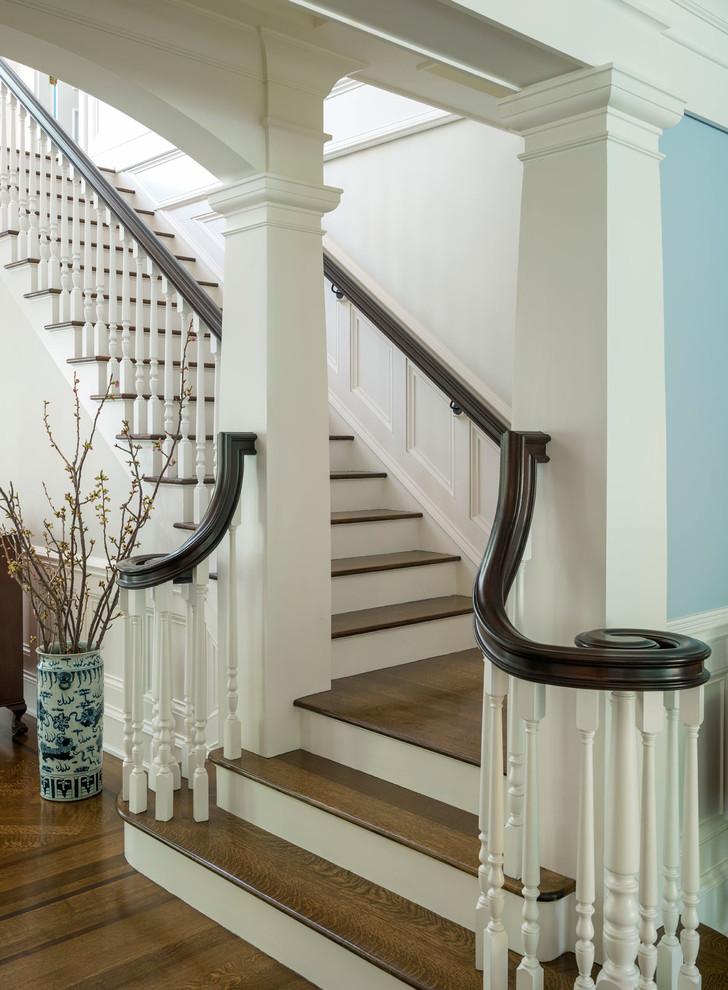 This is an example of a large traditional wood floating staircase in Boston with painted wood risers.