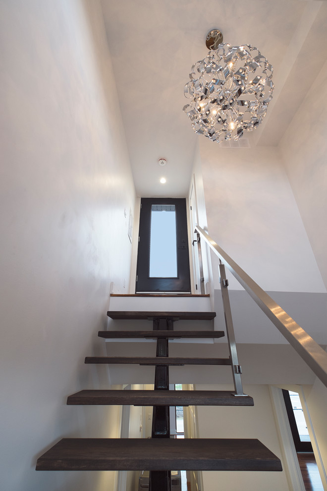 Cette image montre un escalier flottant minimaliste de taille moyenne avec des marches en bois, des contremarches en métal et un garde-corps en matériaux mixtes.
