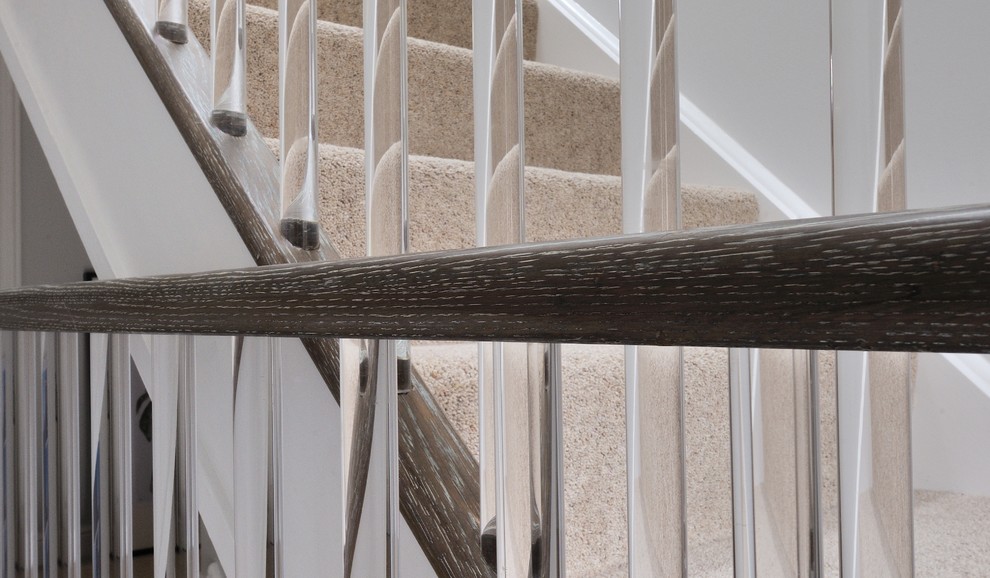 Ejemplo de escalera recta contemporánea de tamaño medio con escalones enmoquetados, contrahuellas de madera y barandilla de madera