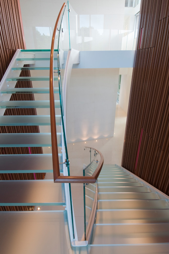Réalisation d'un escalier sans contremarche design en U avec des marches en verre et un garde-corps en verre.