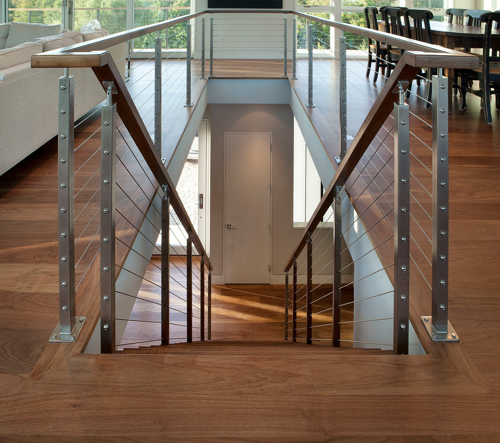 Cette image montre un escalier droit minimaliste de taille moyenne avec un garde-corps en câble et des marches en bois.