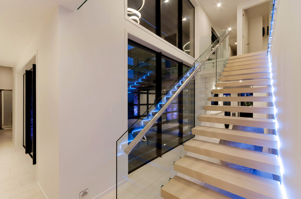 Diseño de escalera suspendida actual grande sin contrahuella con escalones de madera pintada y barandilla de metal