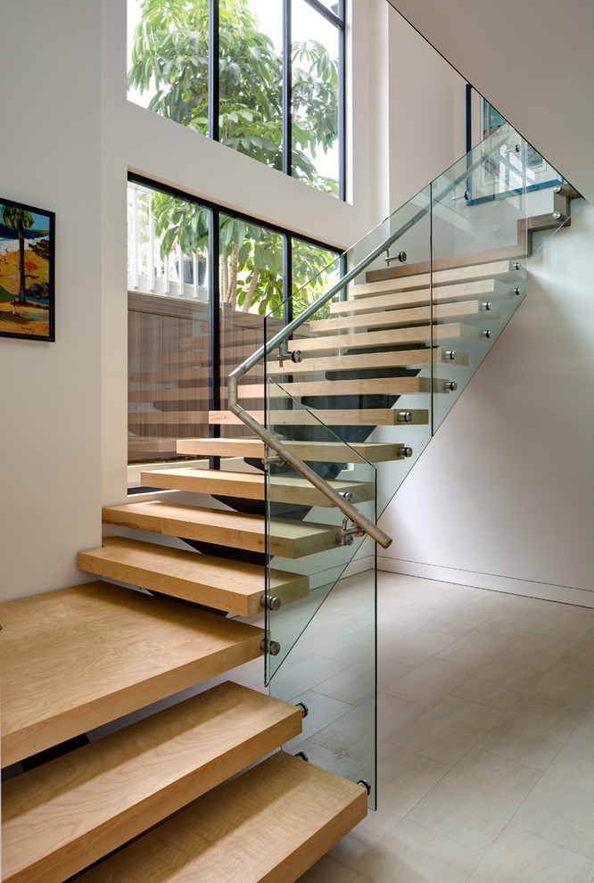 Exempel på en stor modern flytande trappa i trä, med öppna sättsteg och räcke i glas
