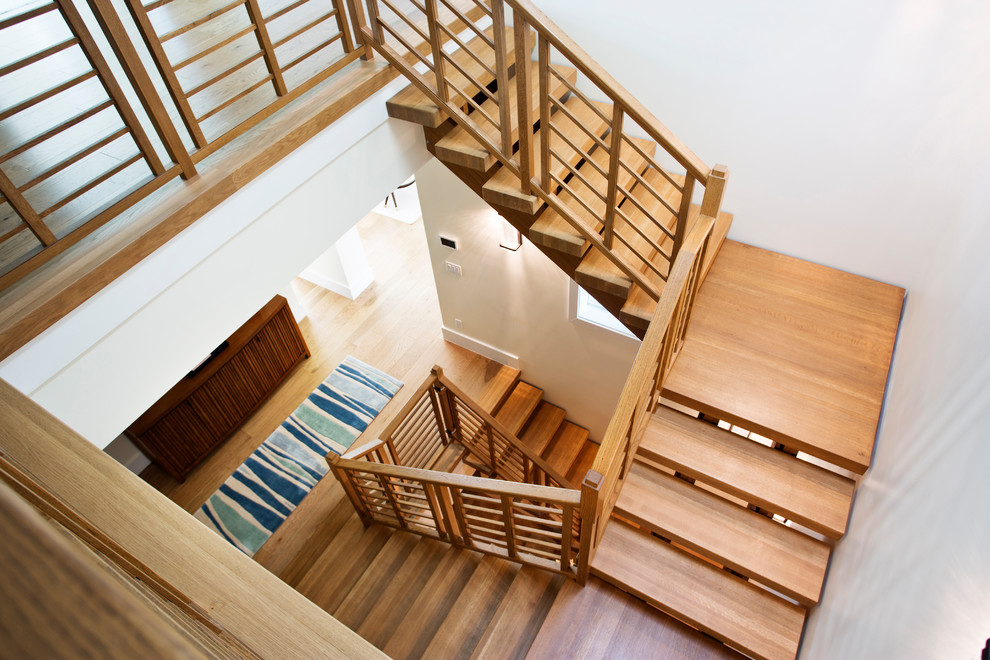 На фото: большая п-образная лестница в стиле модернизм с деревянными ступенями и деревянными перилами без подступенок