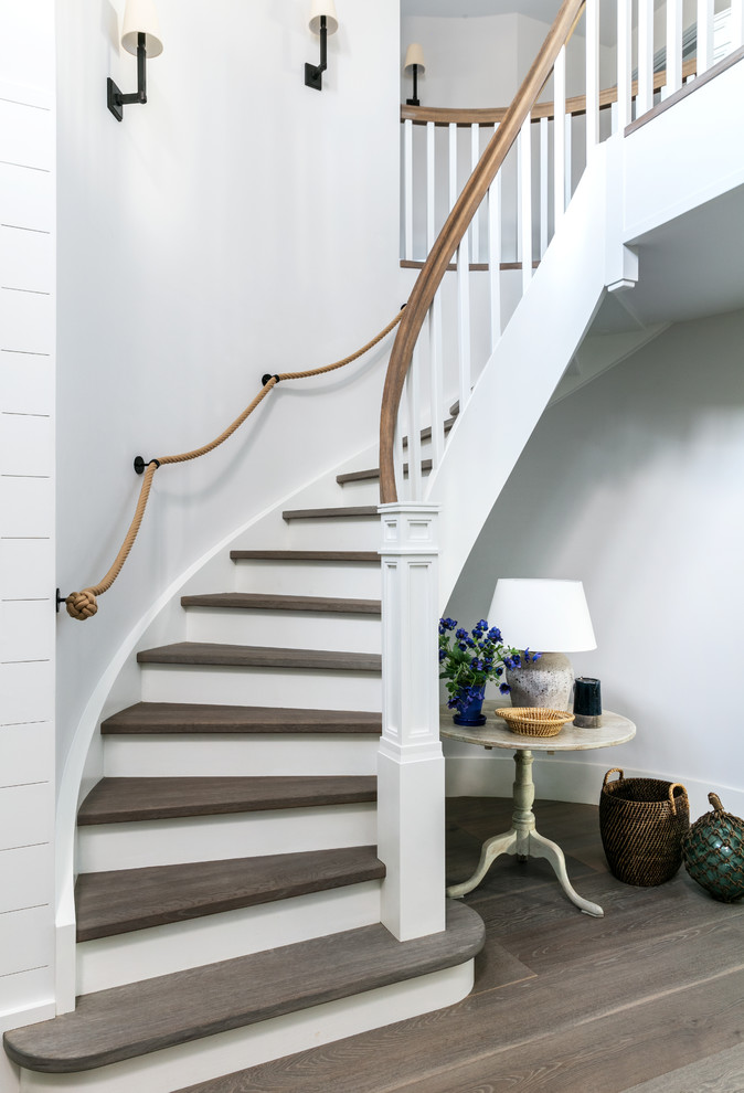 Inspiration for an expansive coastal wood staircase in London with painted wood risers and feature lighting.