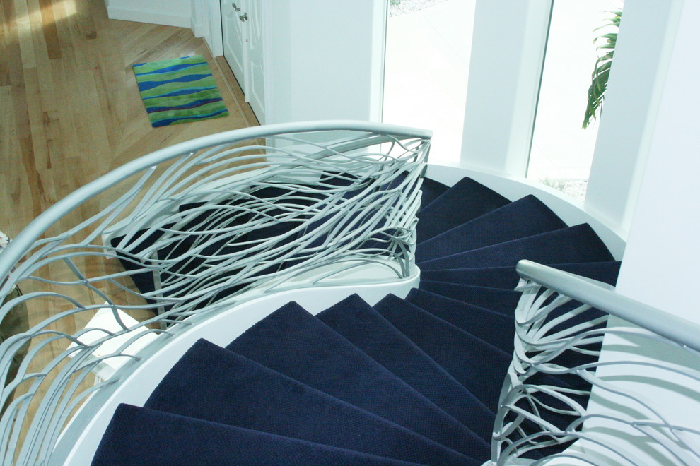 Ejemplo de escalera curva minimalista grande con escalones enmoquetados, contrahuellas enmoquetadas y barandilla de metal