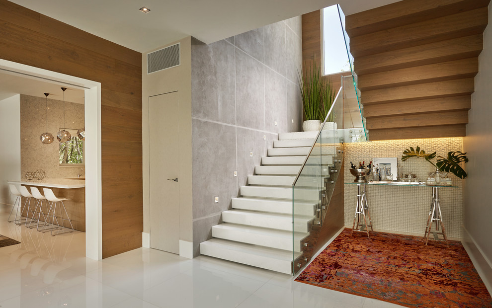 Пример оригинального дизайна: большая п-образная лестница в современном стиле с стеклянными перилами