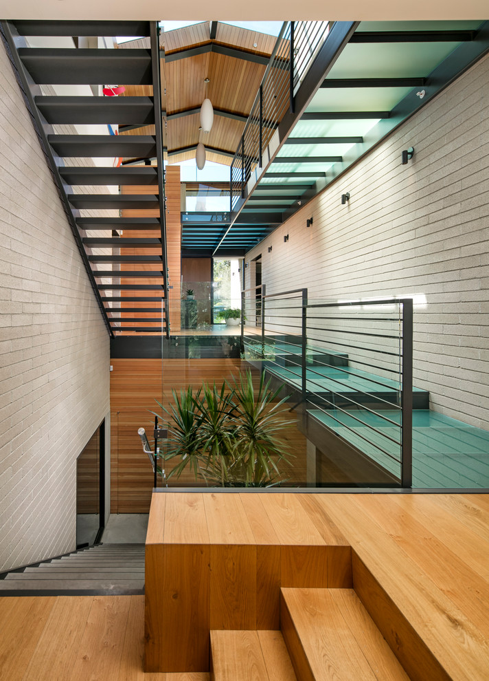 На фото: большая п-образная лестница в стиле ретро с бетонными ступенями и стеклянными перилами без подступенок