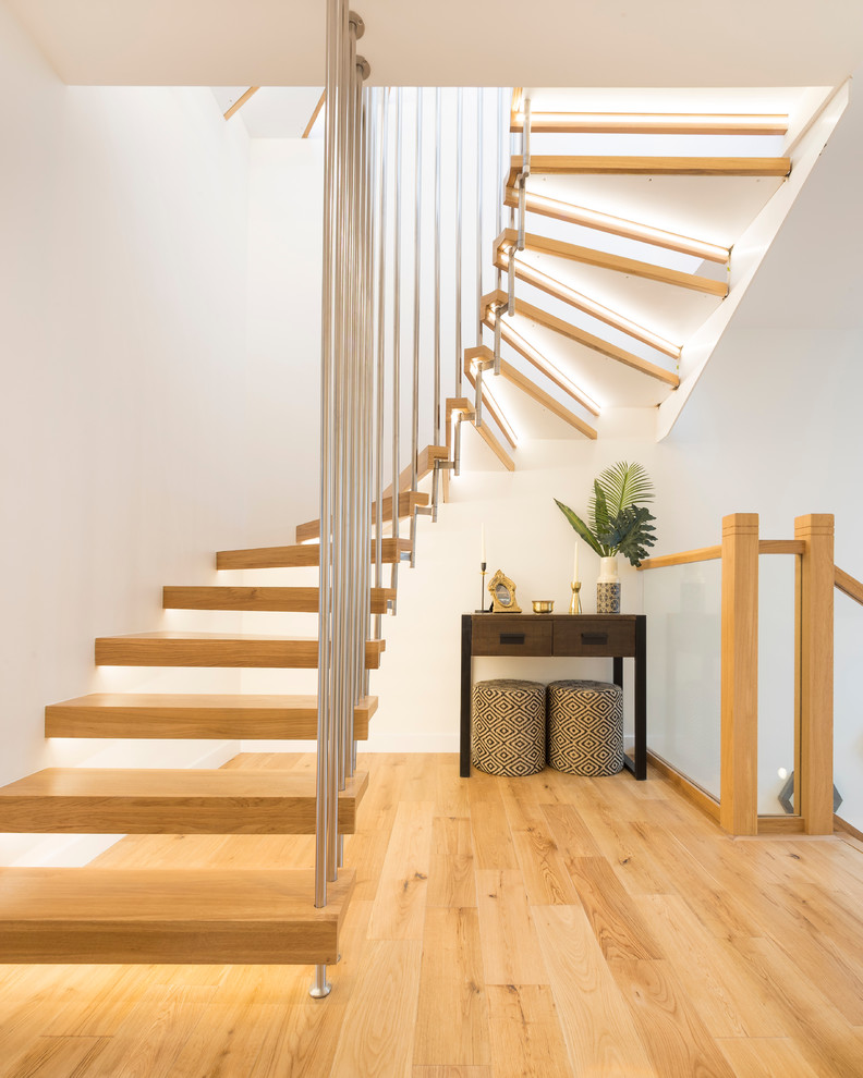 Inspiration för moderna svängda trappor i trä, med öppna sättsteg och räcke i metall