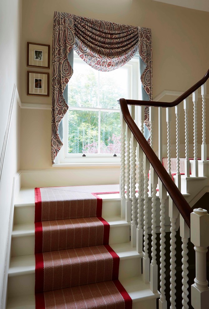 Пример оригинального дизайна: большая винтовая лестница в классическом стиле с ступенями с ковровым покрытием и ковровыми подступенками