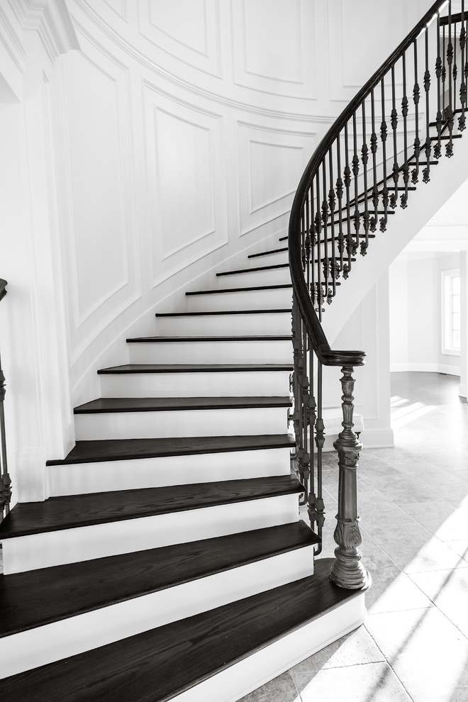 Diseño de escalera curva clásica renovada grande con escalones de madera, contrahuellas de madera y barandilla de metal