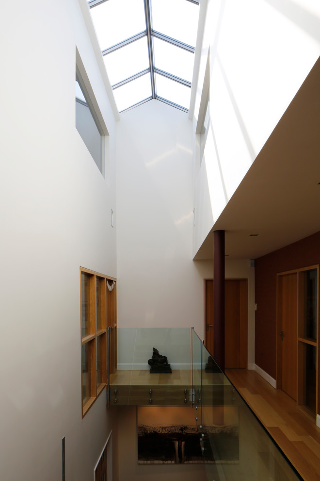Esempio di una grande scala a "L" minimalista con pedata in legno, alzata in legno e parapetto in vetro