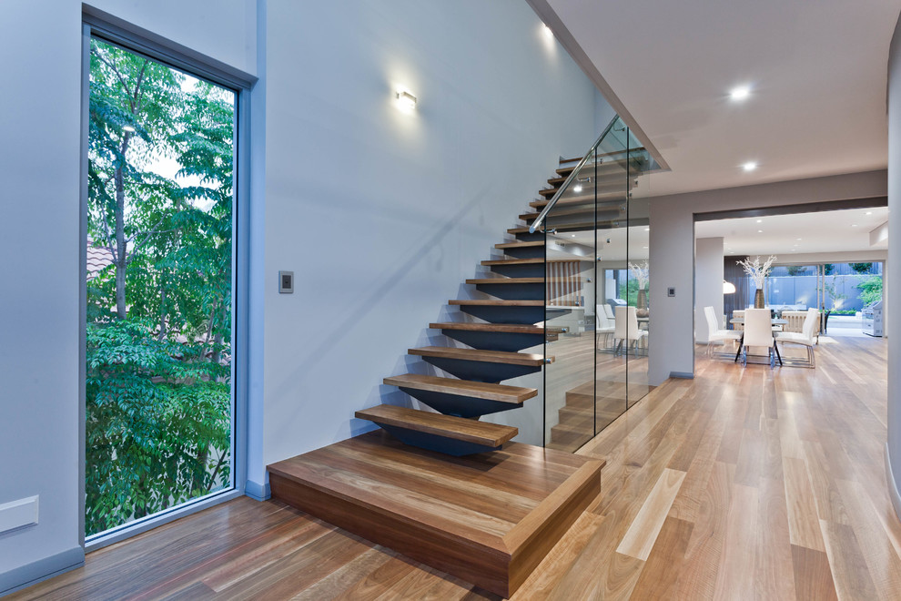 Идея дизайна: прямая лестница среднего размера в современном стиле с деревянными ступенями, стеклянными подступенками и стеклянными перилами