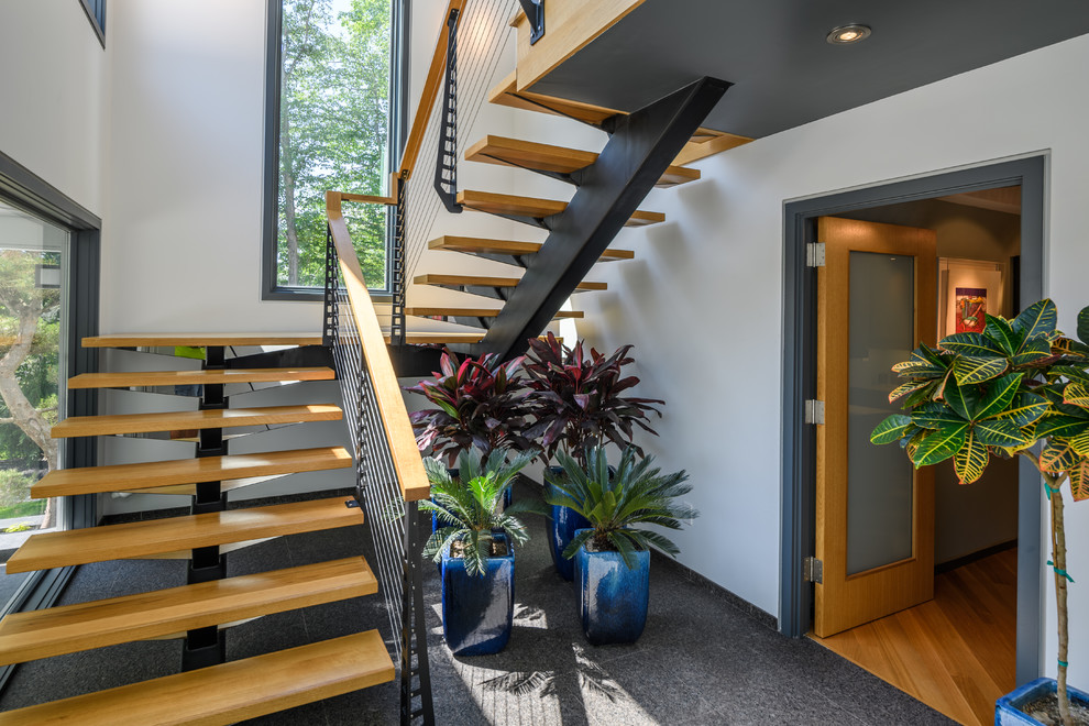 Imagen de escalera suspendida moderna grande sin contrahuella con escalones de madera y barandilla de cable