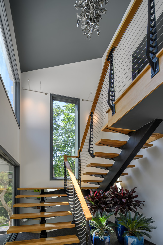 Ejemplo de escalera suspendida moderna grande sin contrahuella con escalones de madera y barandilla de cable