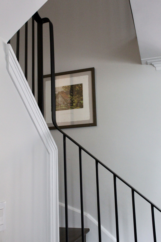 Imagen de escalera curva retro de tamaño medio con escalones de madera, contrahuellas de madera y barandilla de metal