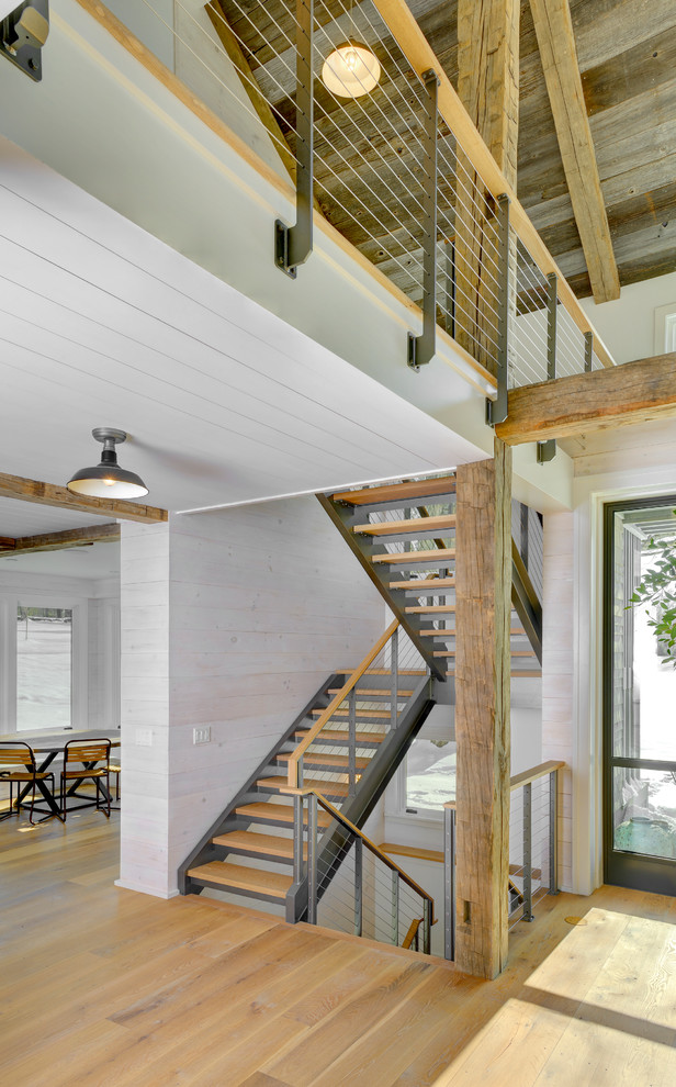 Ejemplo de escalera de estilo de casa de campo con escalones de madera y barandilla de cable