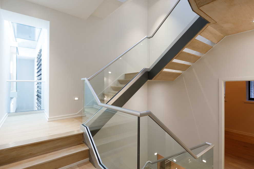 Cette photo montre un grand escalier tendance avec des marches en bois, des contremarches en bois et un garde-corps en métal.