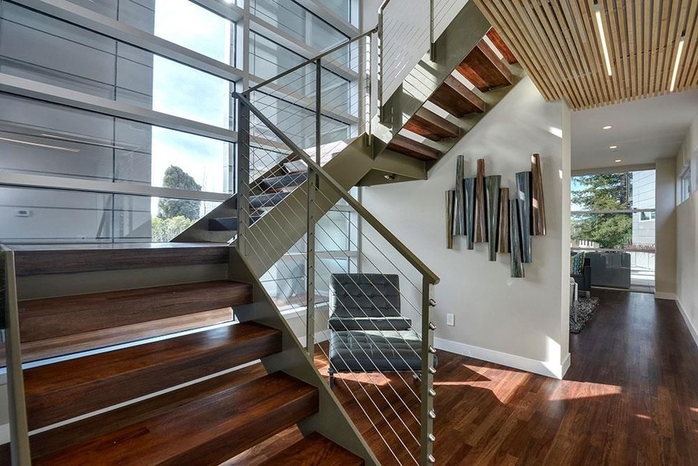 Свежая идея для дизайна: большая п-образная лестница в стиле модернизм с деревянными ступенями и перилами из тросов без подступенок - отличное фото интерьера