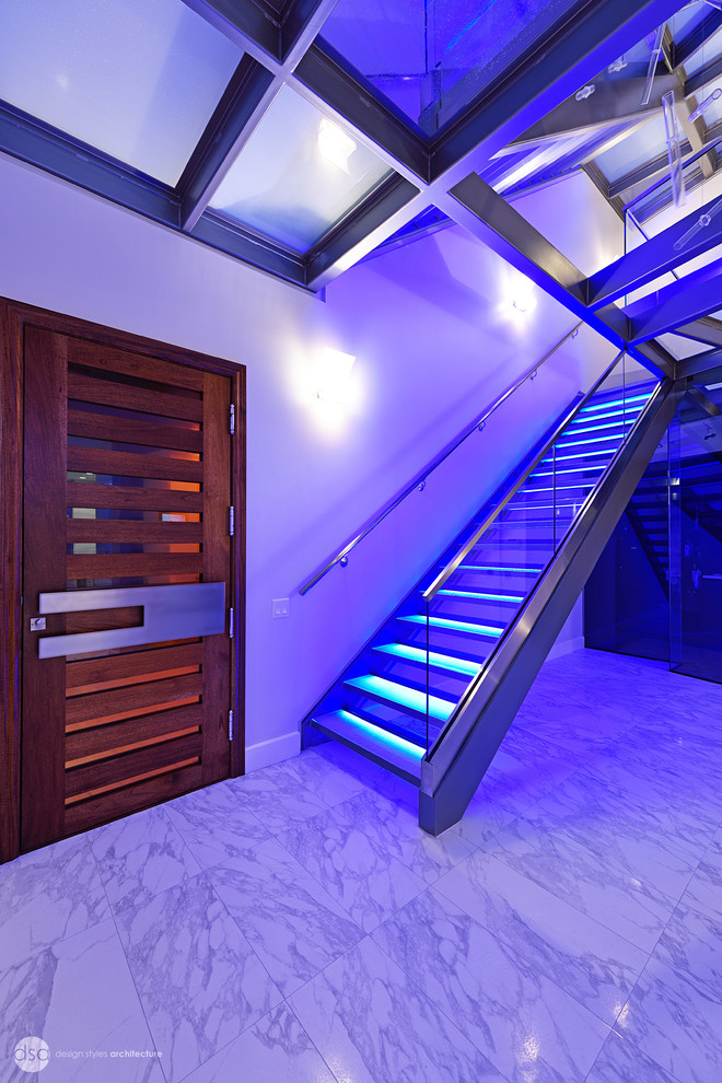 Réalisation d'un grand escalier flottant design avec des marches en métal et des contremarches en verre.