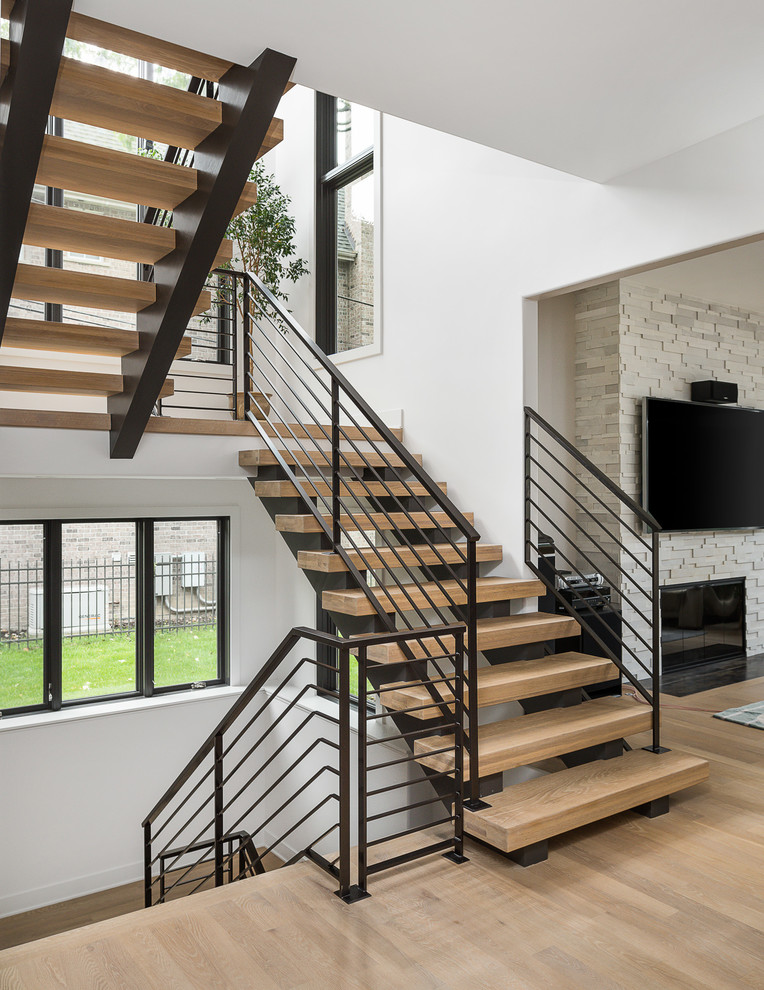 Diseño de escalera suspendida contemporánea grande sin contrahuella con escalones de madera y barandilla de metal