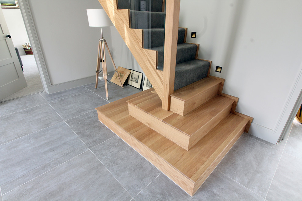 На фото: угловая лестница в современном стиле с ступенями с ковровым покрытием, ковровыми подступенками и деревянными перилами