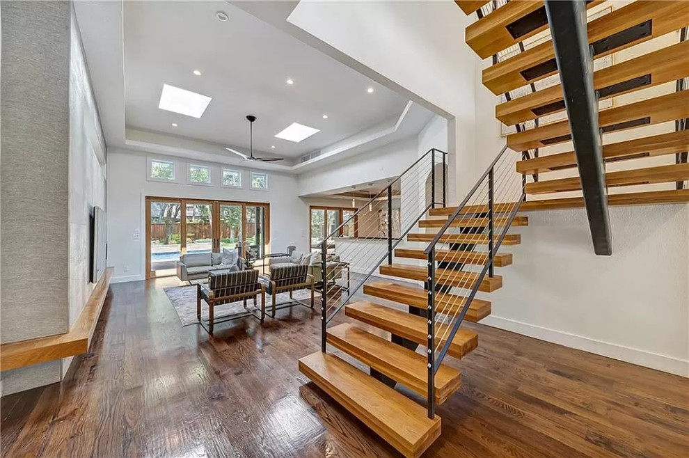 Large contemporary wood floating wire cable railing staircase in Dallas with open risers.