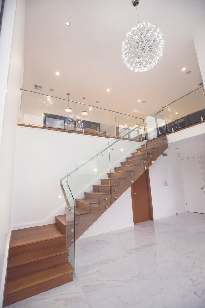 Foto de escalera en L contemporánea de tamaño medio con escalones de madera, contrahuellas de madera y barandilla de vidrio