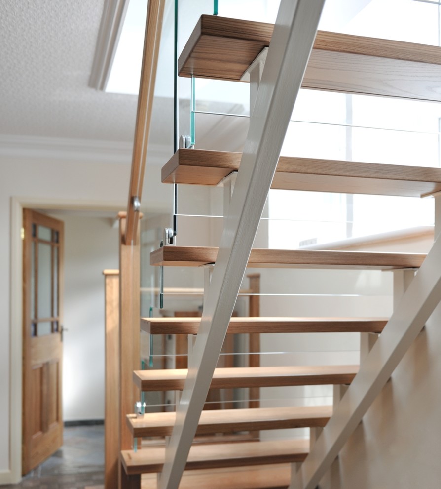 Foto de escalera en L contemporánea de tamaño medio con escalones de madera, contrahuellas de vidrio y barandilla de madera