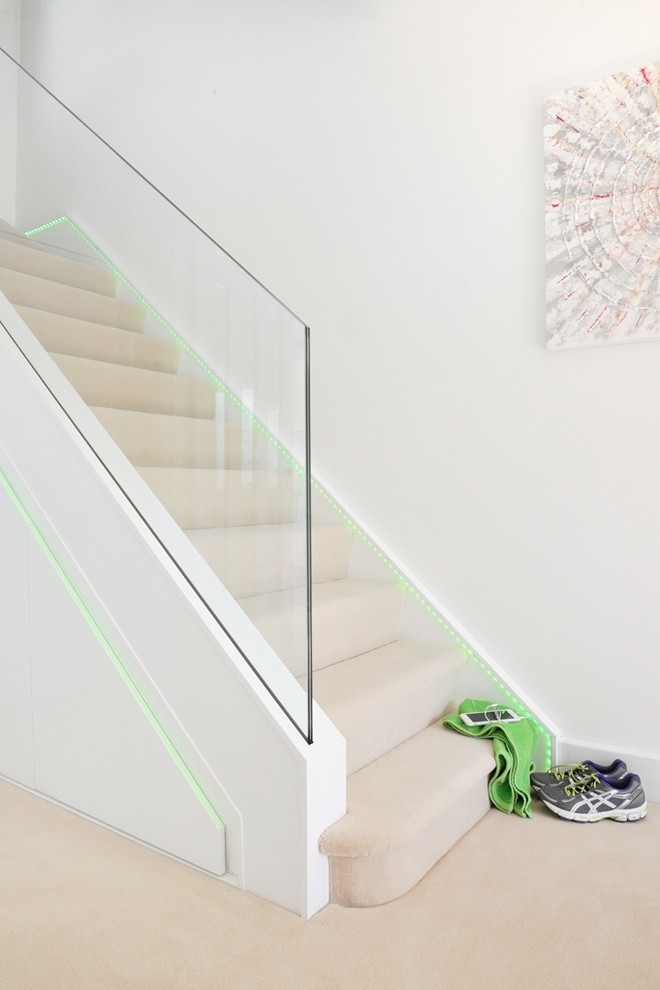 Идея дизайна: большая п-образная лестница в современном стиле с ступенями с ковровым покрытием, стеклянными подступенками и стеклянными перилами
