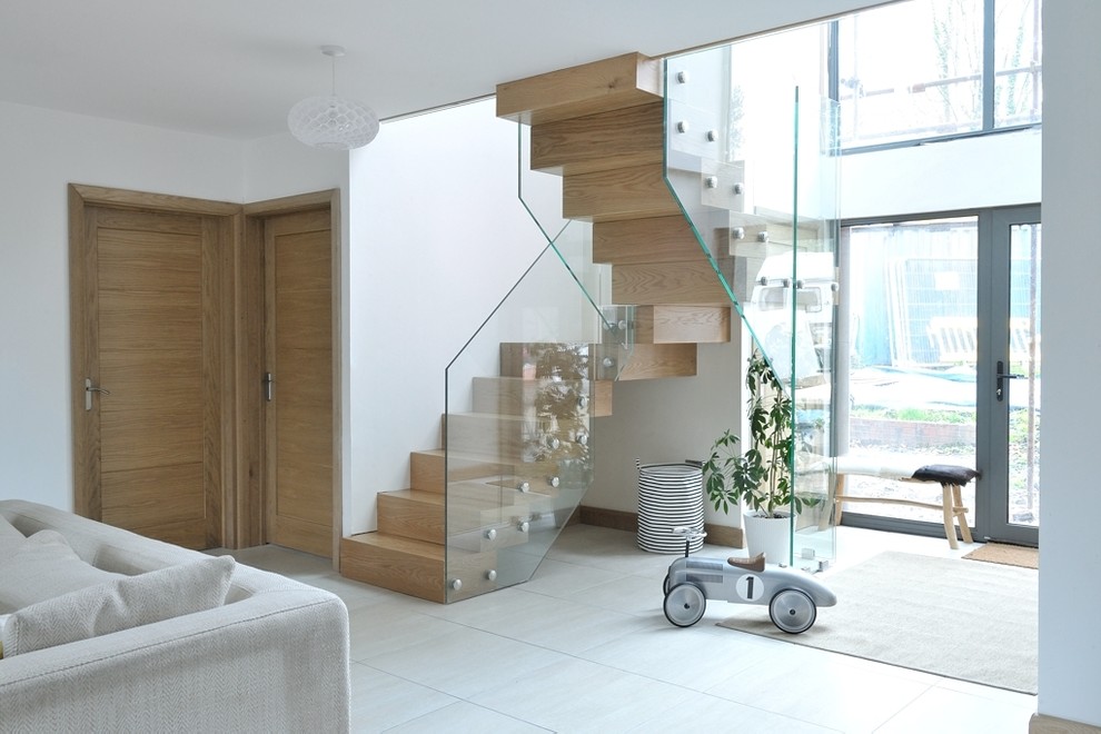 Пример оригинального дизайна: большая изогнутая лестница в современном стиле с деревянными ступенями, стеклянными подступенками и стеклянными перилами