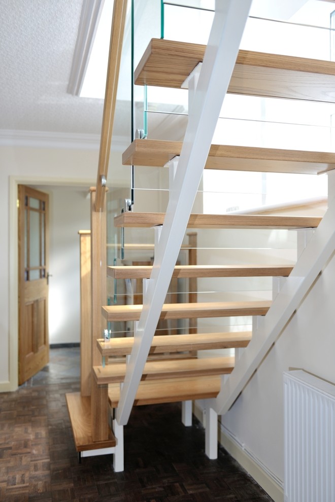 Idée de décoration pour un escalier design en L de taille moyenne avec des marches en bois, des contremarches en verre et un garde-corps en bois.