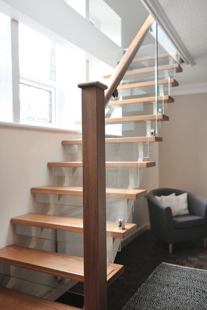 Пример оригинального дизайна: угловая лестница среднего размера в современном стиле с деревянными ступенями, стеклянными подступенками и деревянными перилами